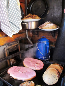 Blueberrry pancakes and breakfast ham share space on the wood cookstove with a kettle. ©Hilary Nangle