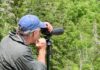A man uses a spotting scope to look for birds in Acadia National Park