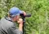 A man uses a spotting scope to look for birds in Acadia National Park