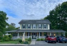 The yellow clapboard Holbrook House in Bar Harbor as seen from the sidewalk across the street.