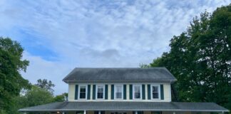 The yellow clapboard Holbrook House in Bar Harbor as seen from the sidewalk across the street.