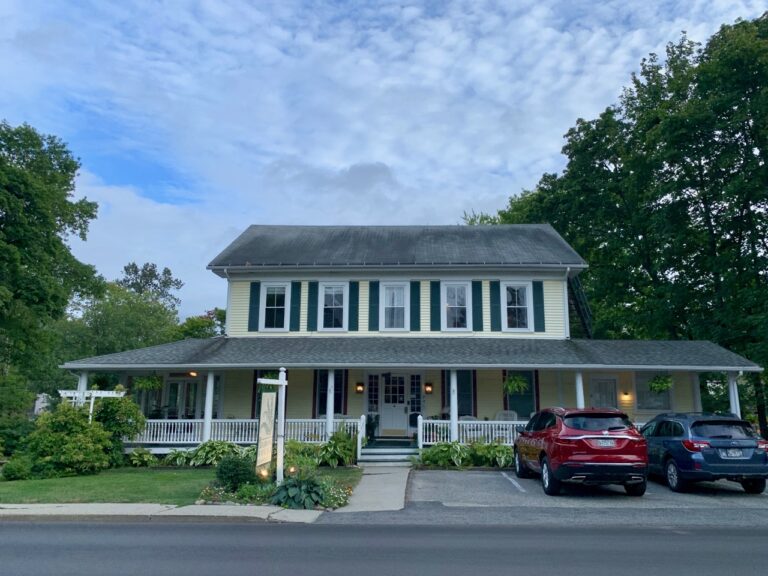 The yellow clapboard Holbrook House in Bar Harbor as seen from the sidewalk across the street.