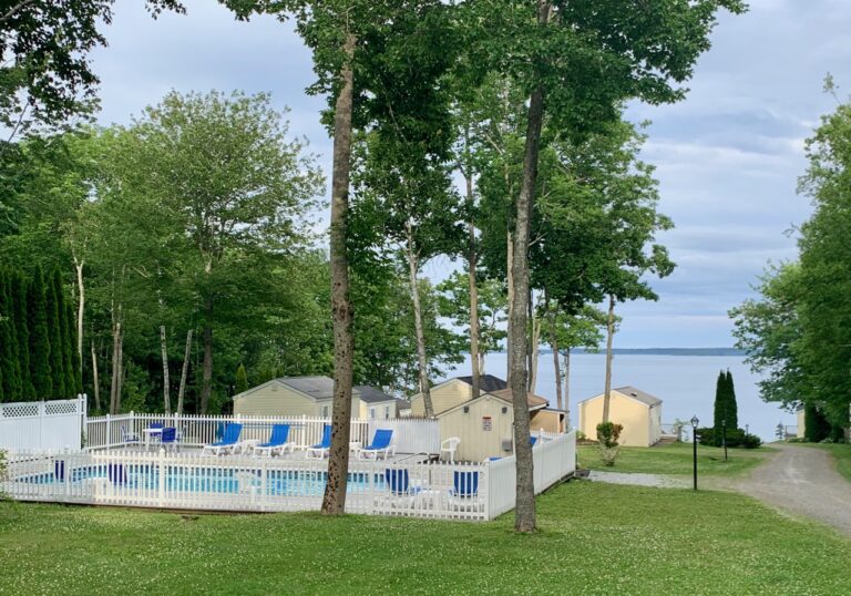 View taking in the pool, staggered cottages, and Penobscot Bay taken from above the lower pool at Glenmoor by the Sea.